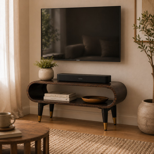 Curved solid mango wood TV media unit with brass-tipped legs styled in a small UK living room.